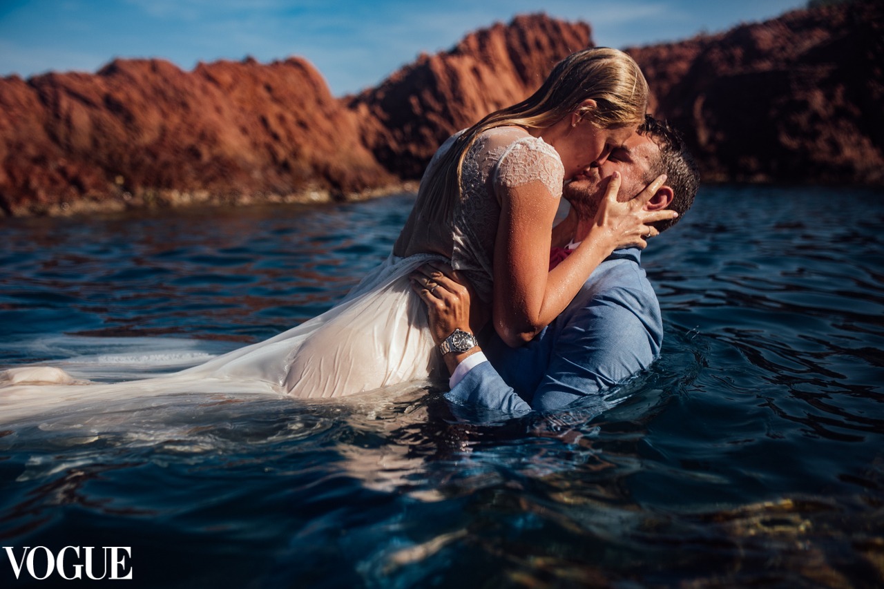 Wedding photographer — a couple embracing in the sea below red cliffs